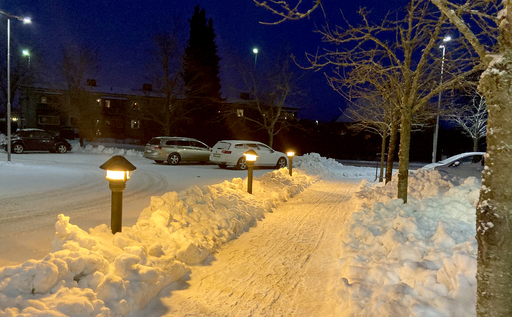 En gångväg med snö och stolpar med lyse